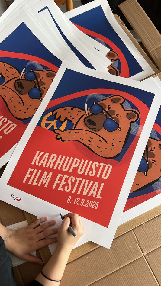Taiteilija Taru Liikanen signeeraamassa Karhupuisto Film Festival taidejulisteita