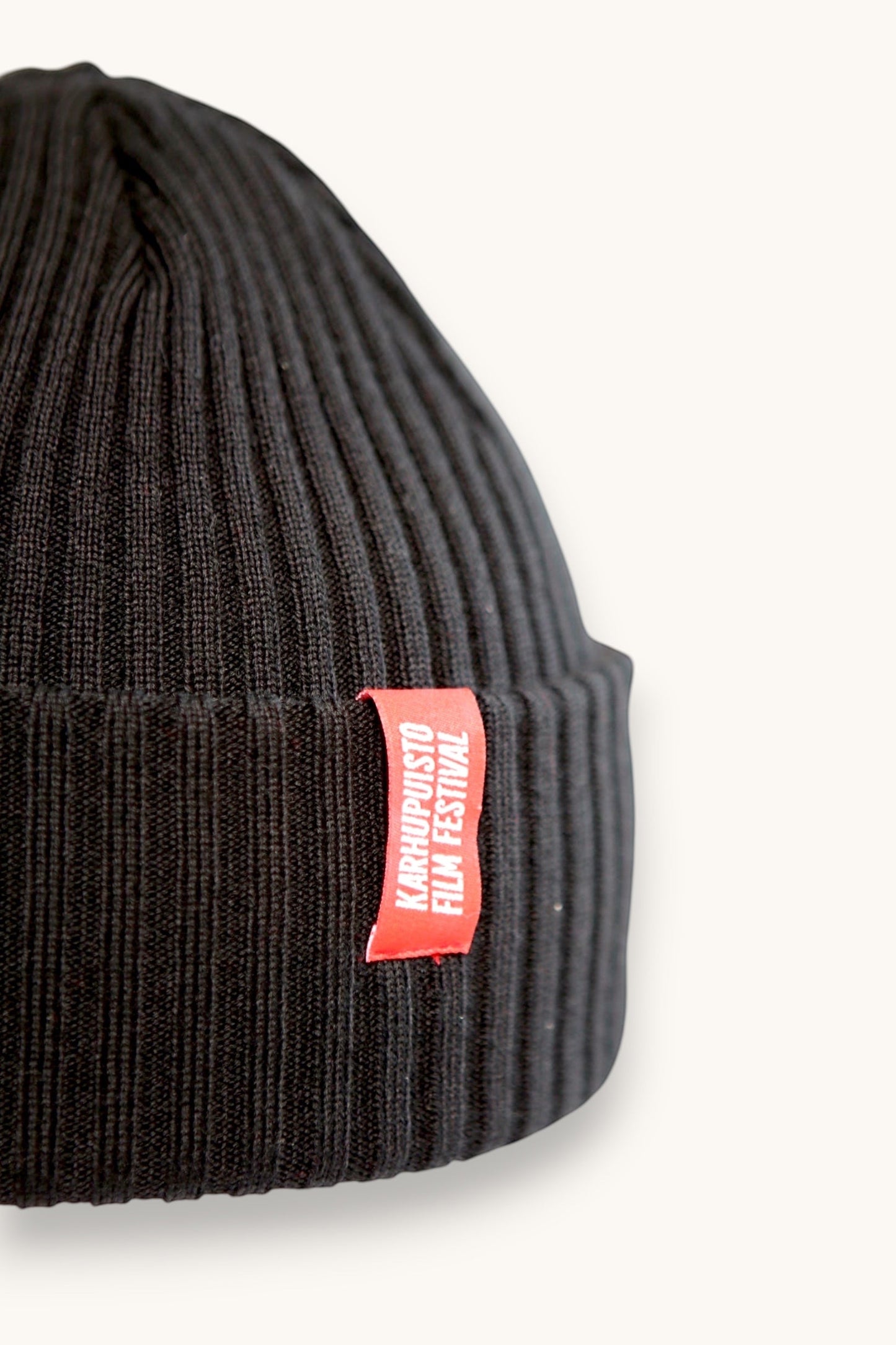 Karhupuisto Film Festival black ribbed knit beanie with a folded cuff and a vibrant red branded woven label.