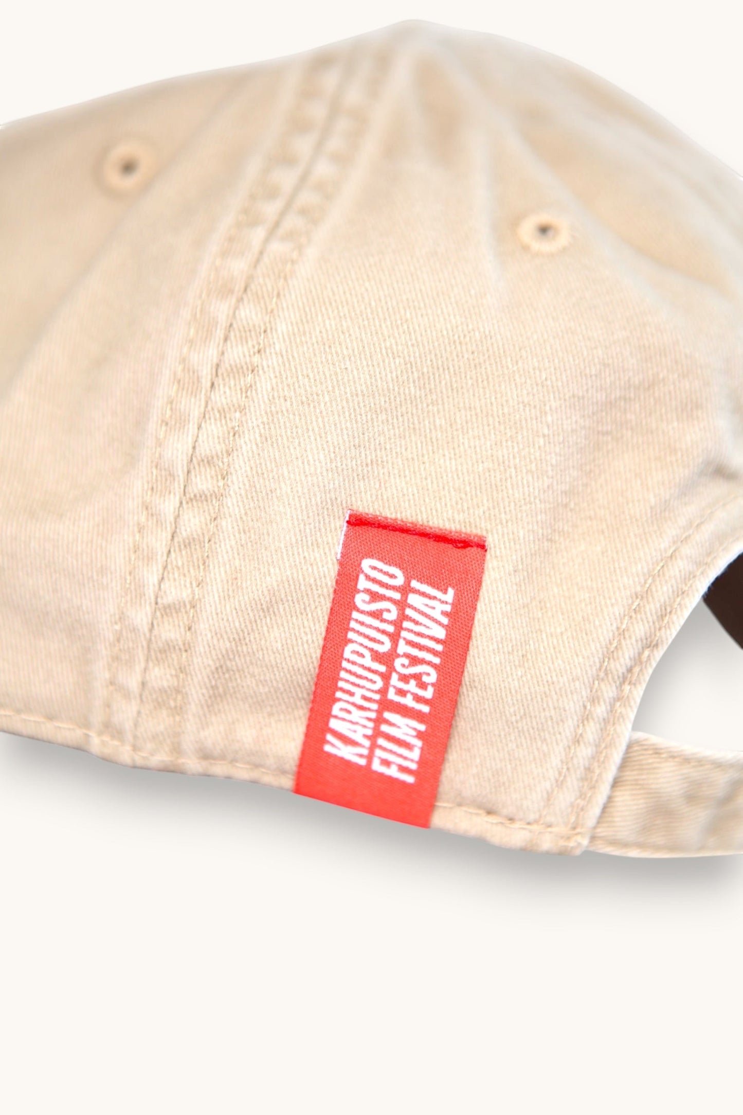 Karhupuisto Film Festival beige cotton baseball cap featuring a red branded side tab with white text
