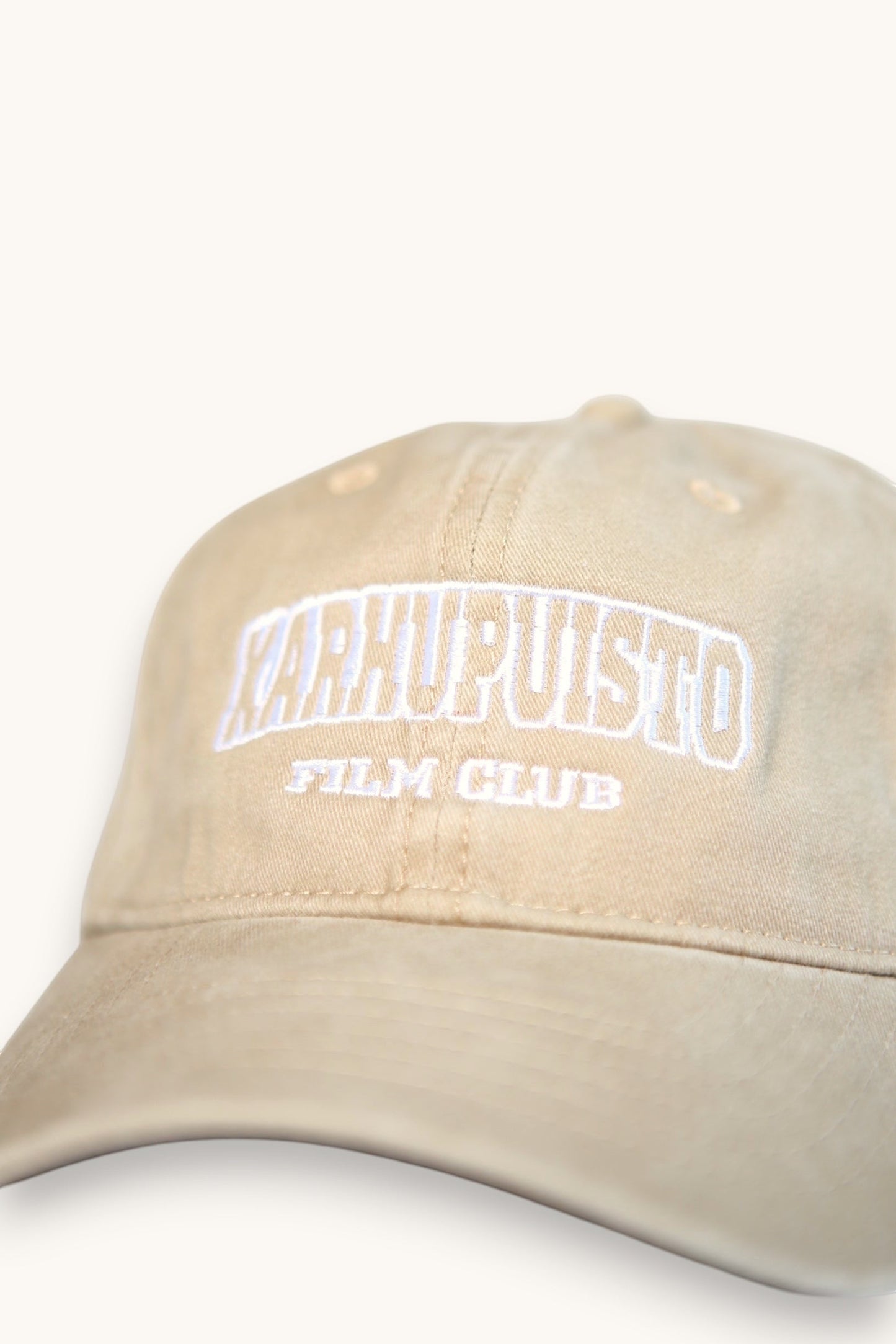 Karhupuisto Film Festival beige cotton baseball cap with white collegiate-style embroidered lettering on the front.