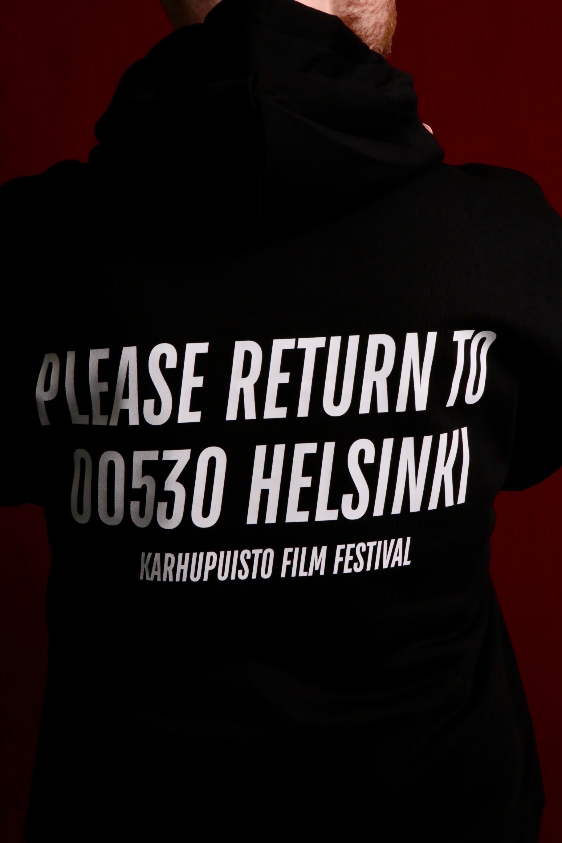 Back view of a black Karhupuisto Film Festival unisex hoodie featuring white text print on the back.