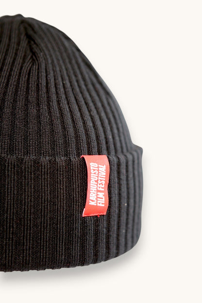 Karhupuisto Film Festival black ribbed knit beanie with a folded cuff and a vibrant red branded woven label.