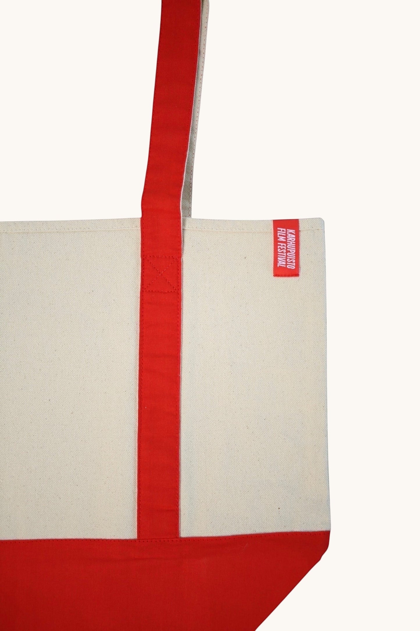 Karhupuisto Film Festival cream recycled cotton canvas tote bag with red handles and base and branded side tag