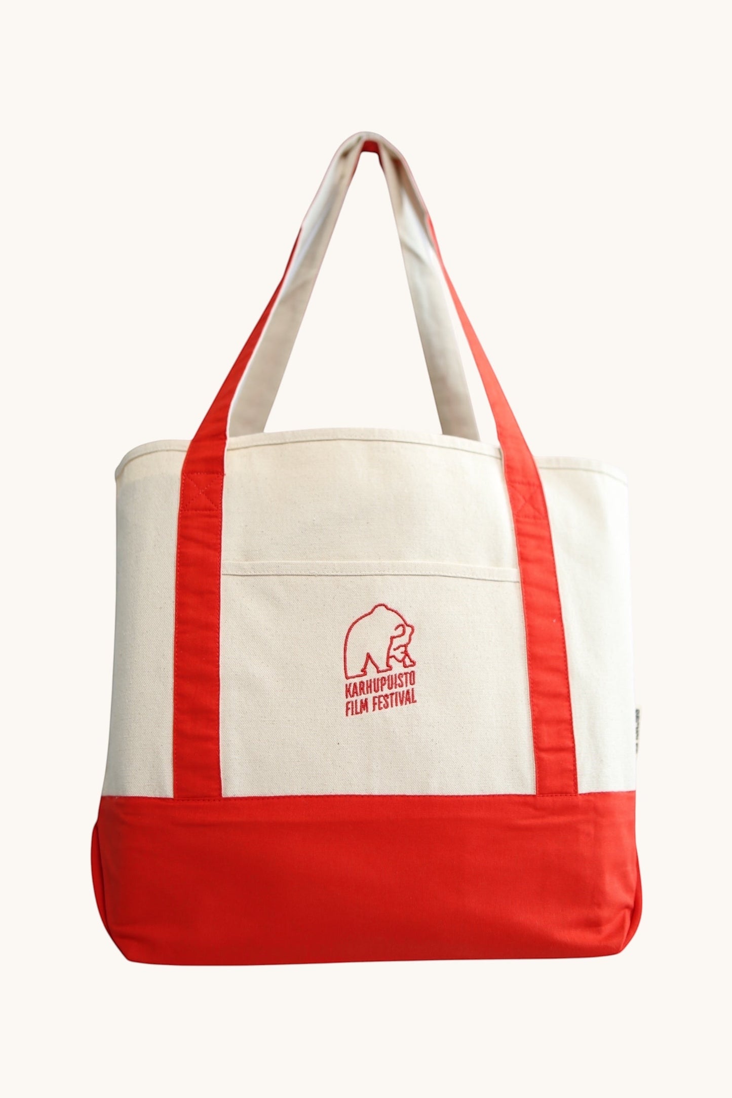 Karhupuisto Film Festival recycled cream cotton canvas tote bag with red handles, base, and bear logo pocket.