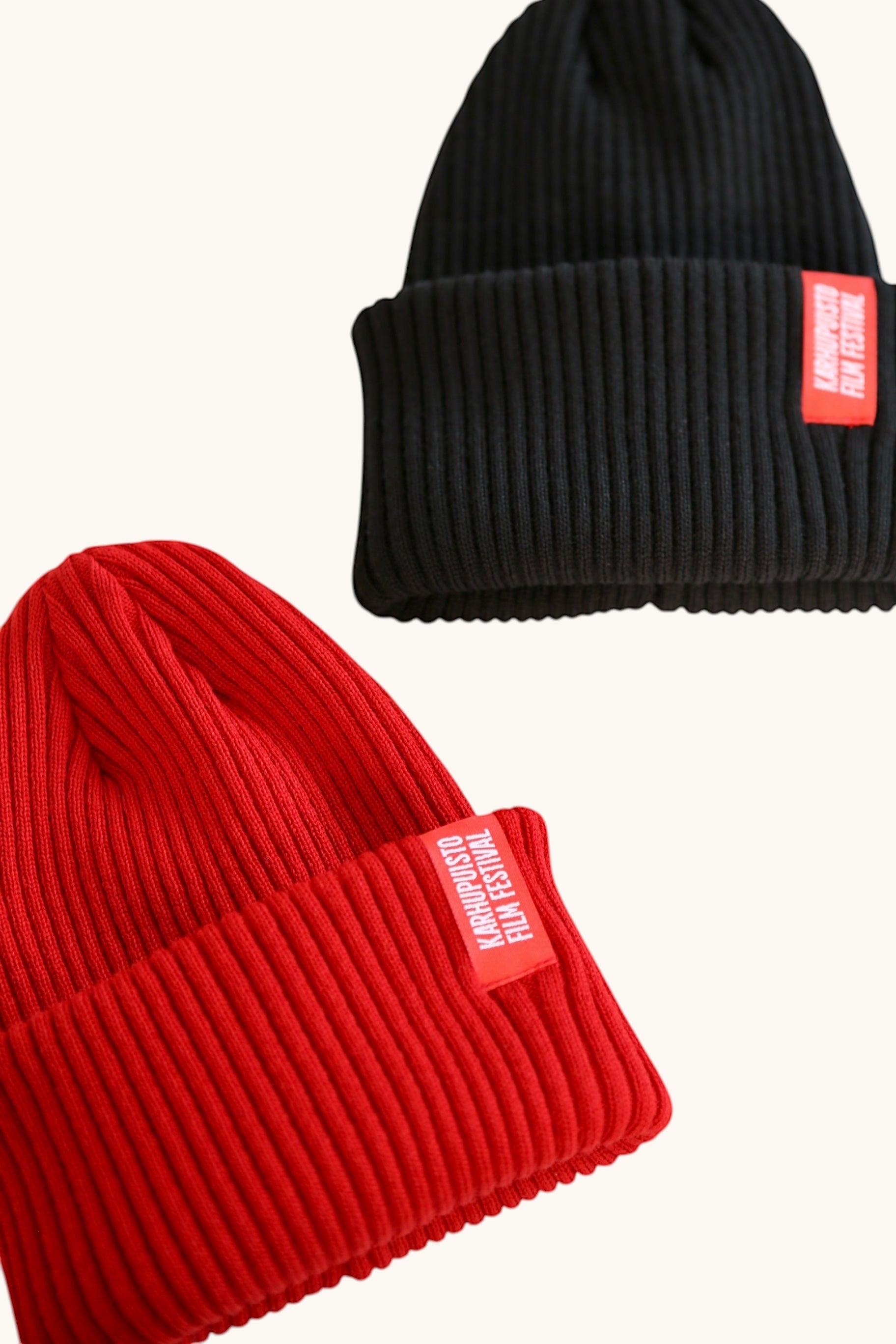 Karhupuisto Film Festival ribbed knit beanies in red and black with branded woven labels on the cuffs.