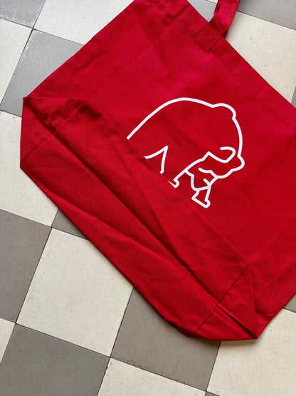 Karhupuisto Film Festival red cotton tote bag with white bear logo print on a tiled floor