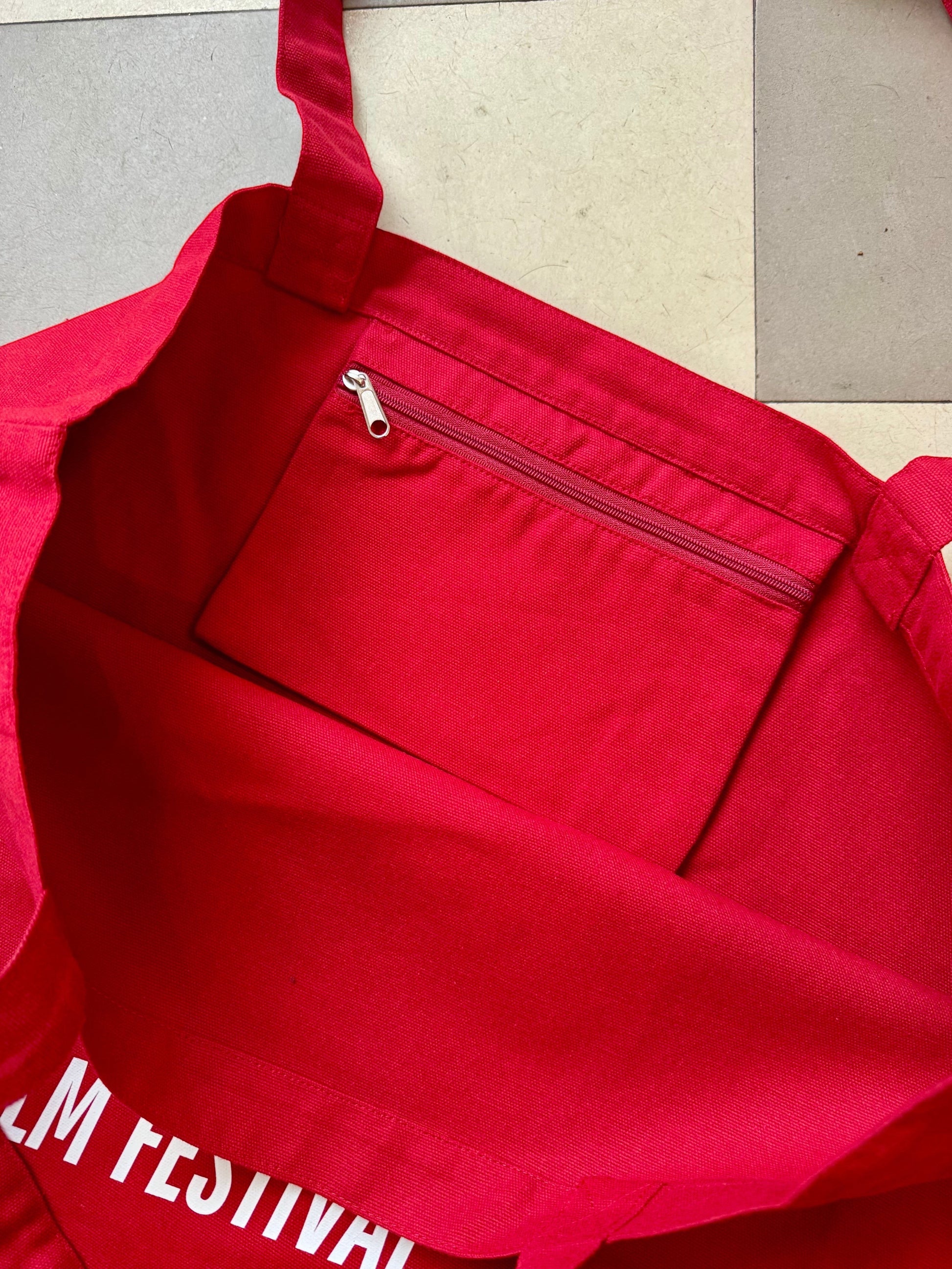 Karhupuisto Film Festival red cotton tote bag with an interior zippered pocket and sturdy handles