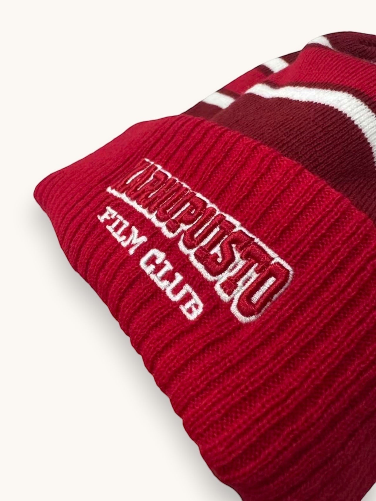 Karhupuisto Film Festival red and burgundy knit pom-pom beanie with white stripes and embroidered logo on ribbed cuff