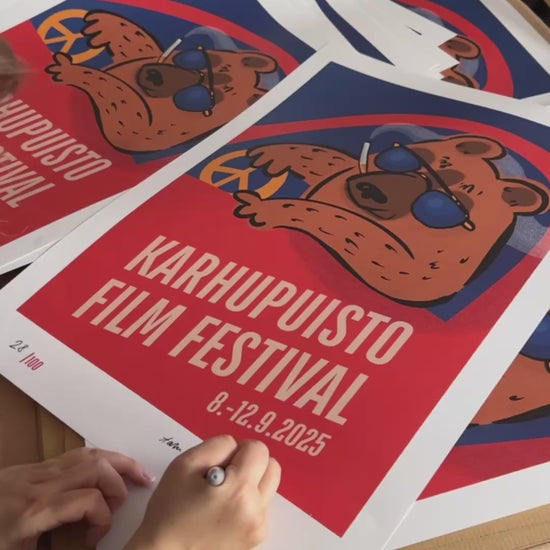Taiteilija Taru Liikanen signeeraamassa Karhupuisto Film Festival taidejulisteita