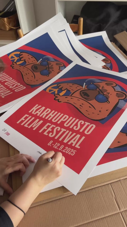 Taiteilija Taru Liikanen signeeraamassa Karhupuisto Film Festival taidejulisteita