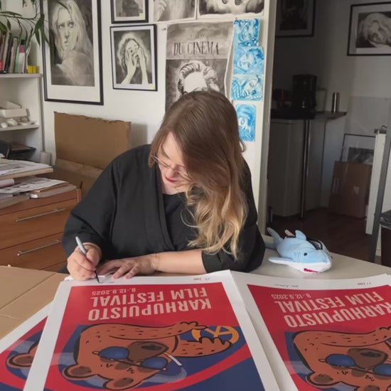 Taiteilija Taru Liikanen signeeraamassa Karhupuisto Film Festival taidejulisteita